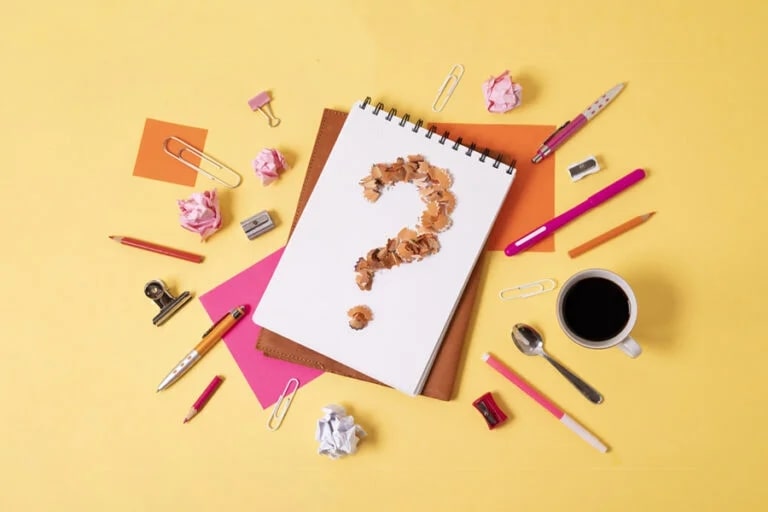 Notebook with a question mark surrounded by crumpled paper and stationery