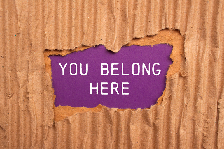 Torn cardboard revealing the words "You belong here"